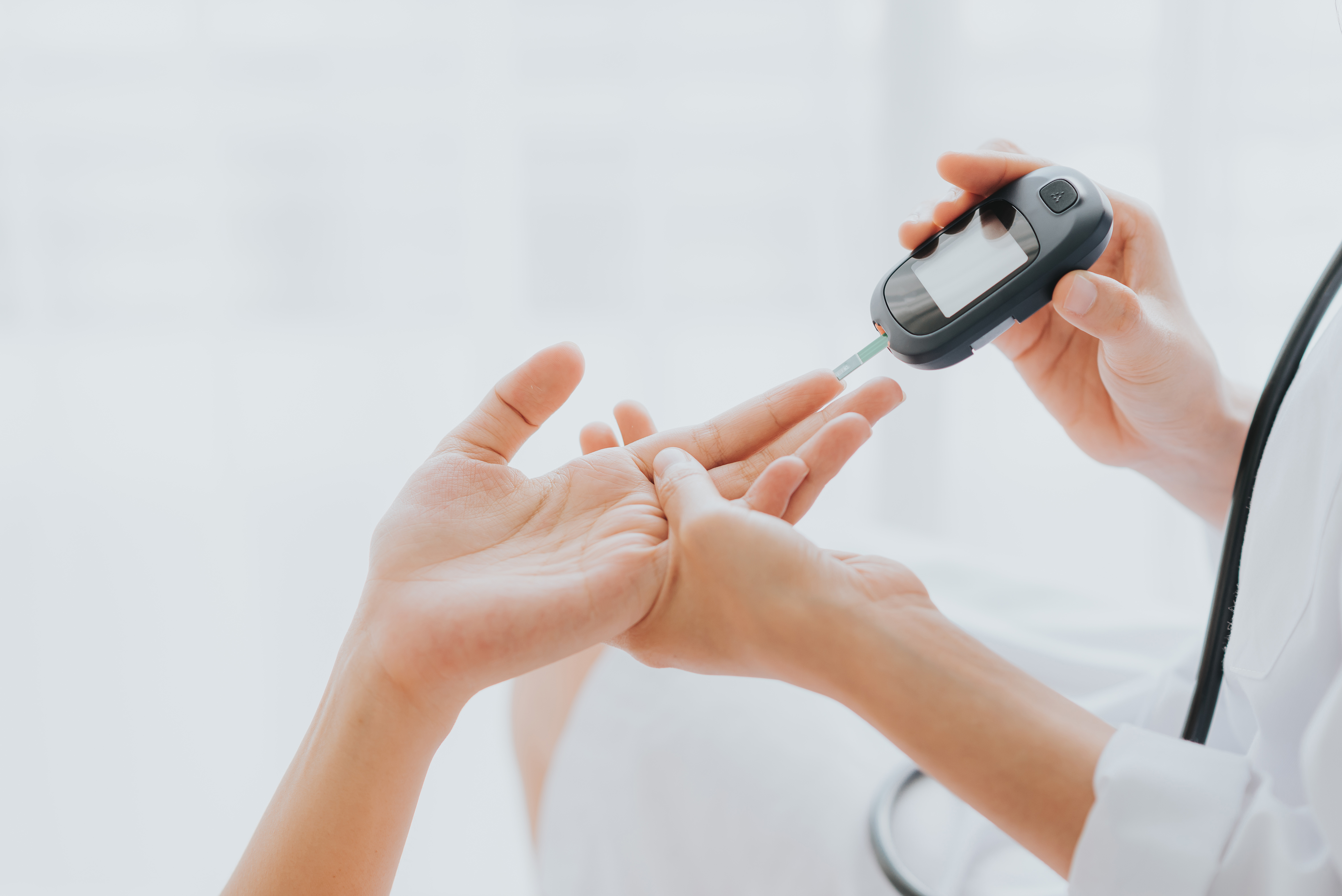Person uses a blood glucose lancing device on a fingertip for diabetes care at Henry Ford Health.