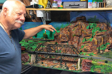 ENT patient Albert pointing at his train set landscape