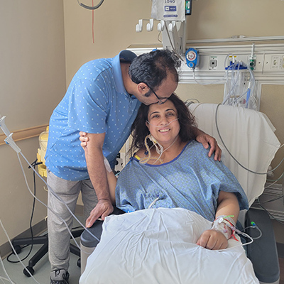 cardiology-patient-amber in a hospital bed while husband kisses her forehead