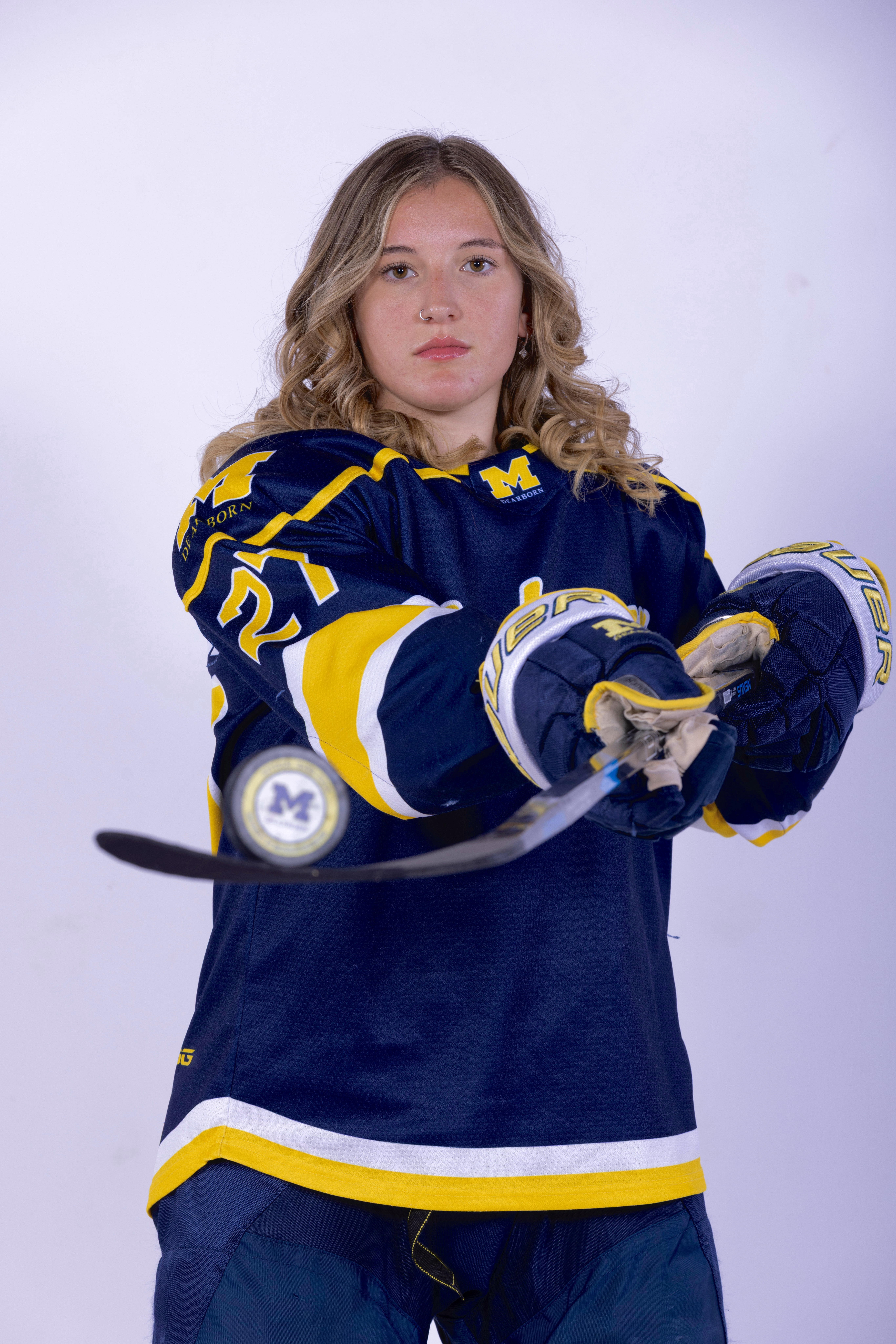 Grace posing with hockey puck on stick.